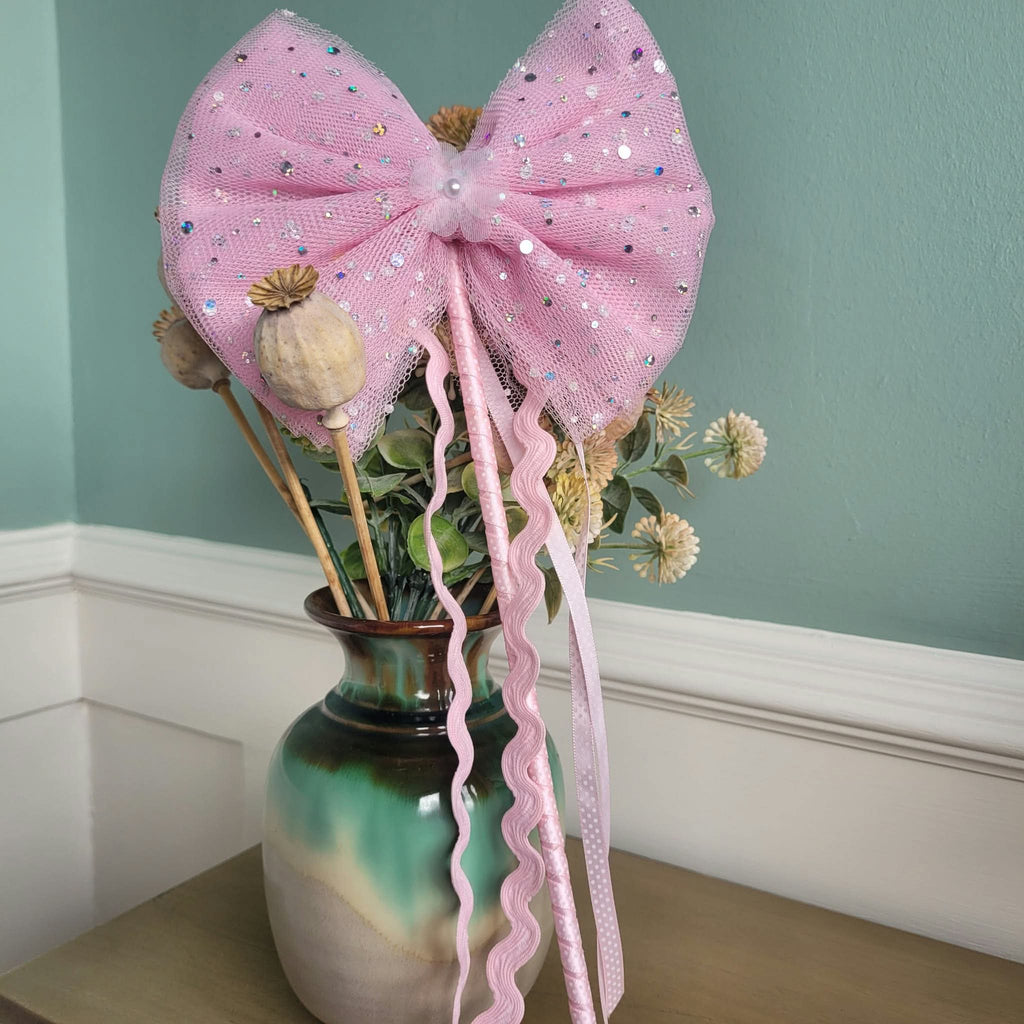 Pink wand with oversized sequin-speckled tulle bow and flowing pink ribbon streamers