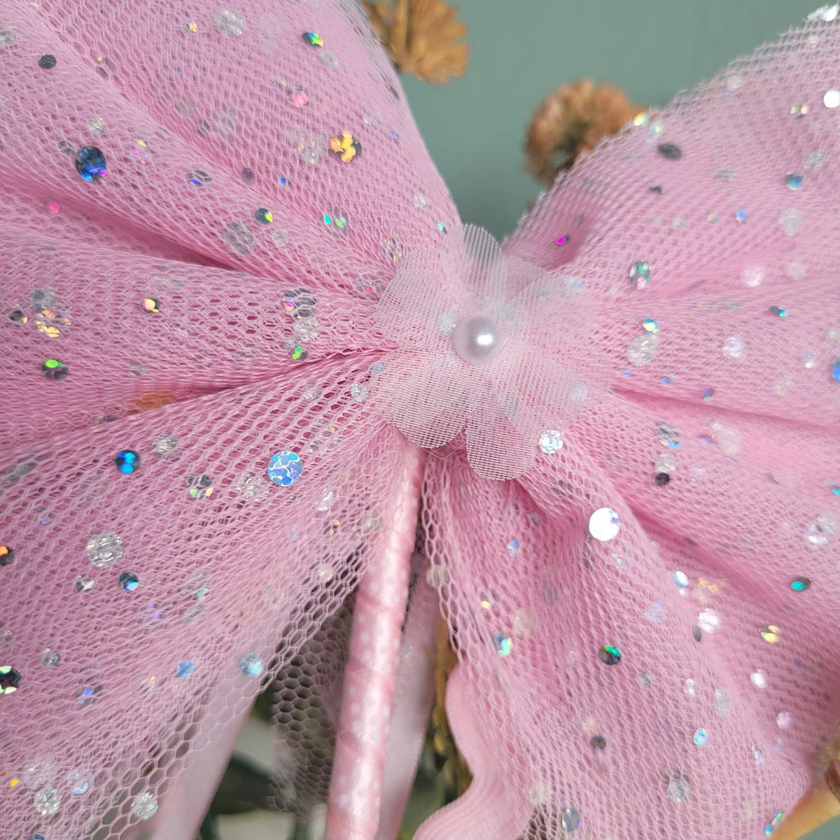 Close-up of sequins on pink tulle bow and pearl-like flower centre of wand