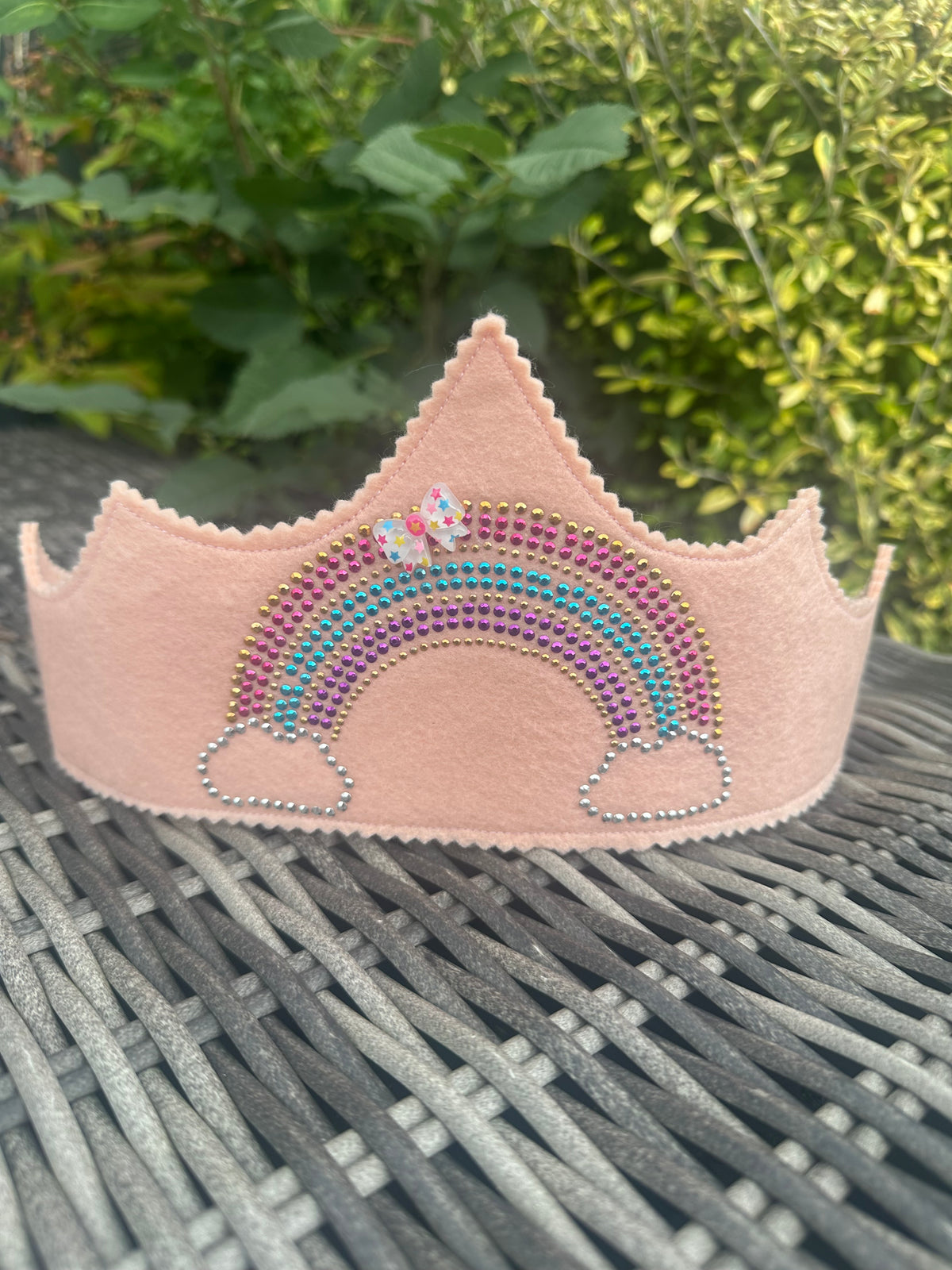 Blush pink felt crown with sparkling multicoloured rhinestone rainbow design and floral bow
