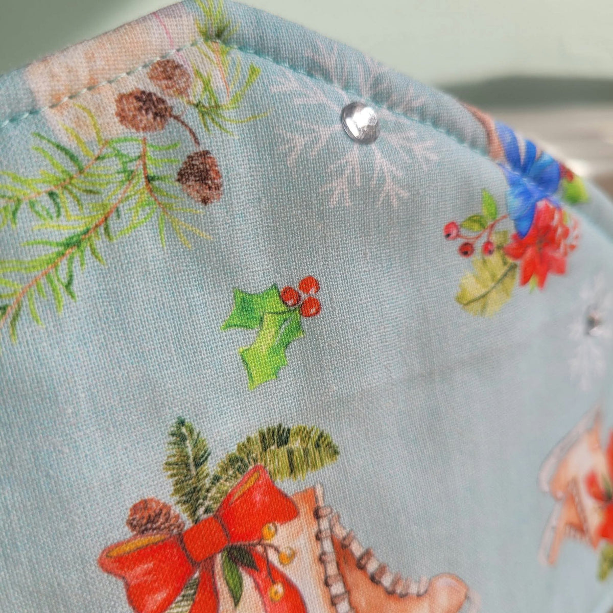 Close-up of pale blue crown with holly, ice skate print and sparkling gem detail