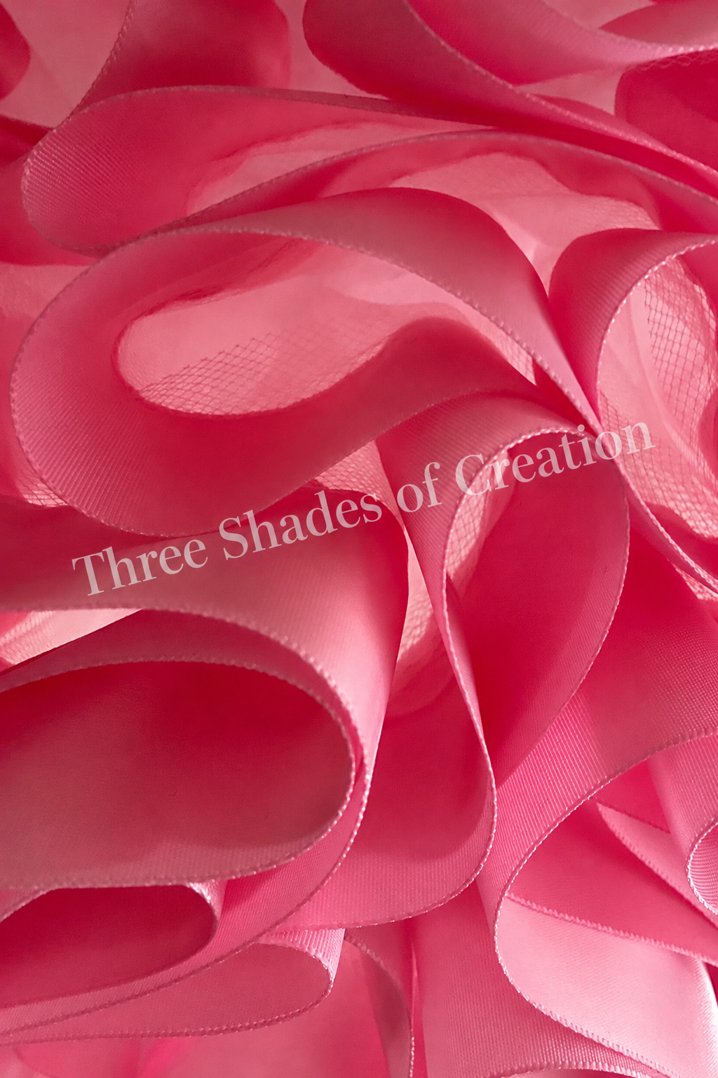 Pink satin ribbon close-up with translucent Three Shades of Creation watermark