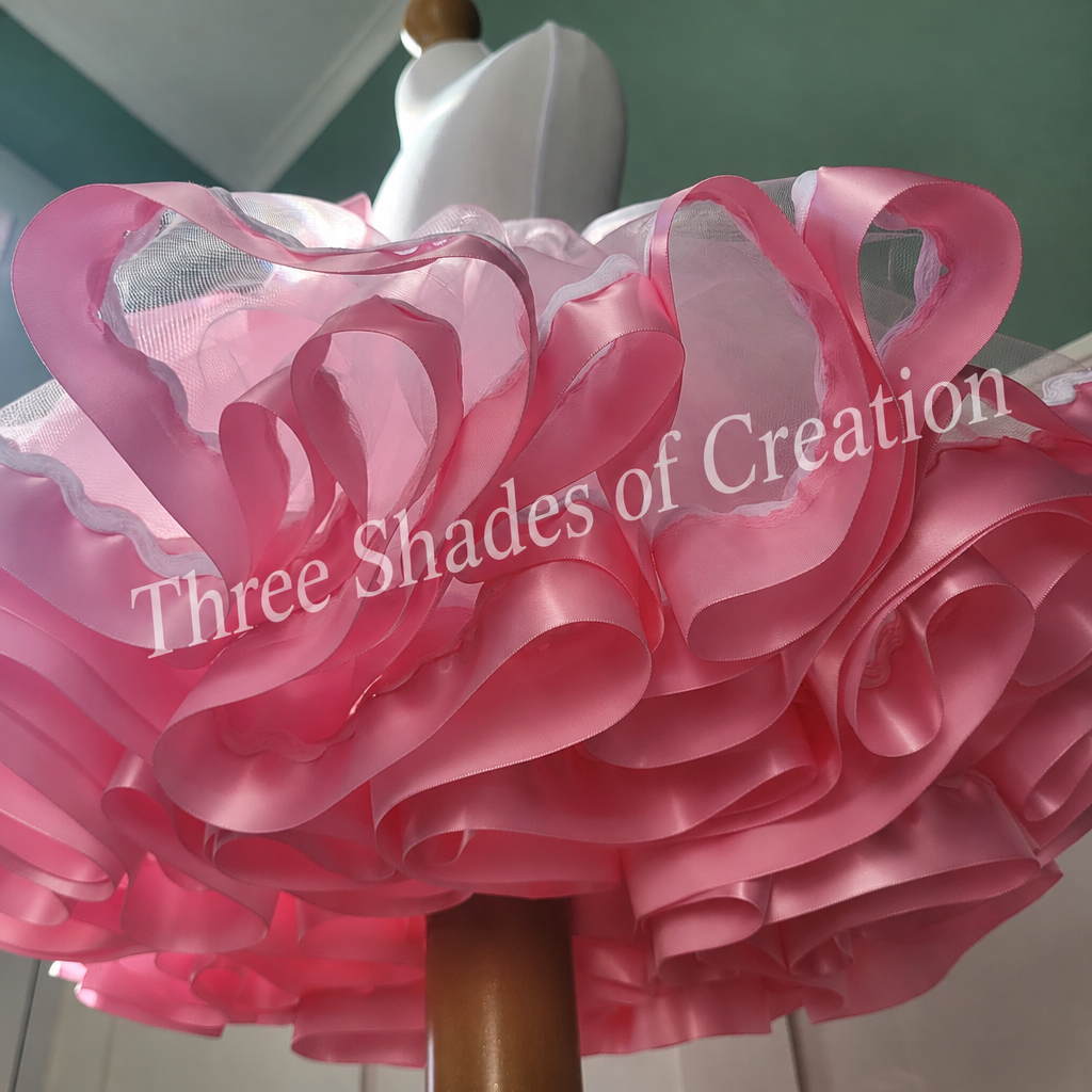 Pink satin ribbon detail with translucent Three Shades of Creation watermark