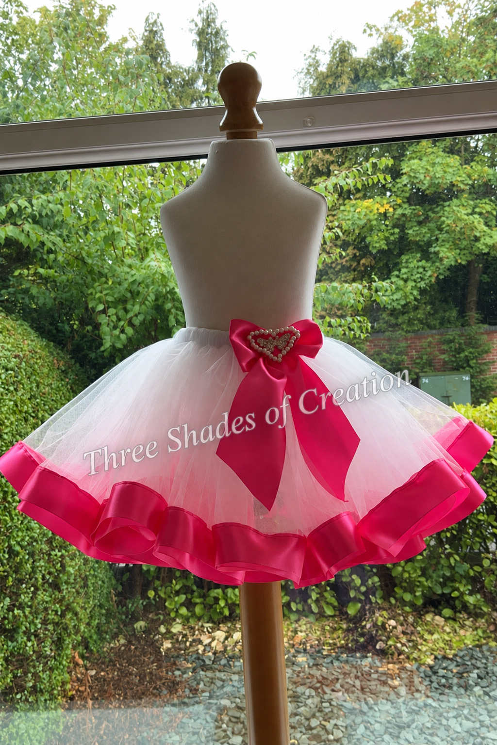 White and cerise tutu by window with translucent Three Shades of Creation watermark
