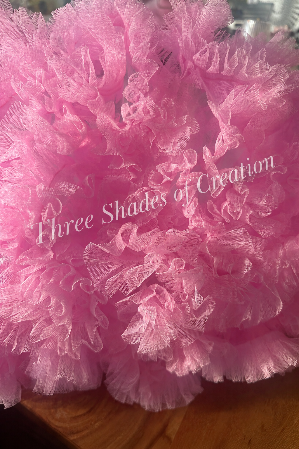 Pink tulle ruffle close-up with translucent Three Shades of Creation watermark