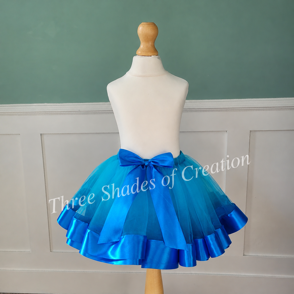 Teal and royal-blue tutu front view with translucent Three Shades of Creation watermark