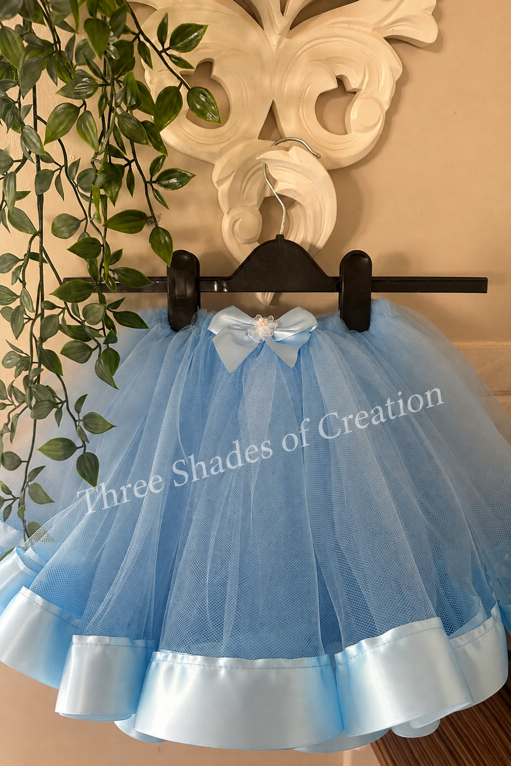 Baby blue tutu on hanger with translucent Three Shades of Creation watermark