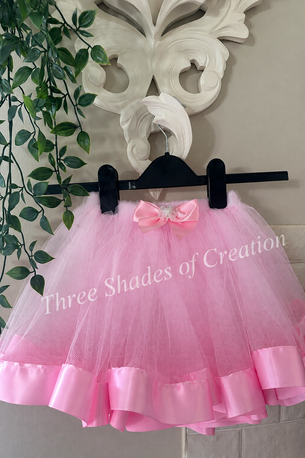 Pink satin trim tutu on hanger with translucent Three Shades of Creation watermark