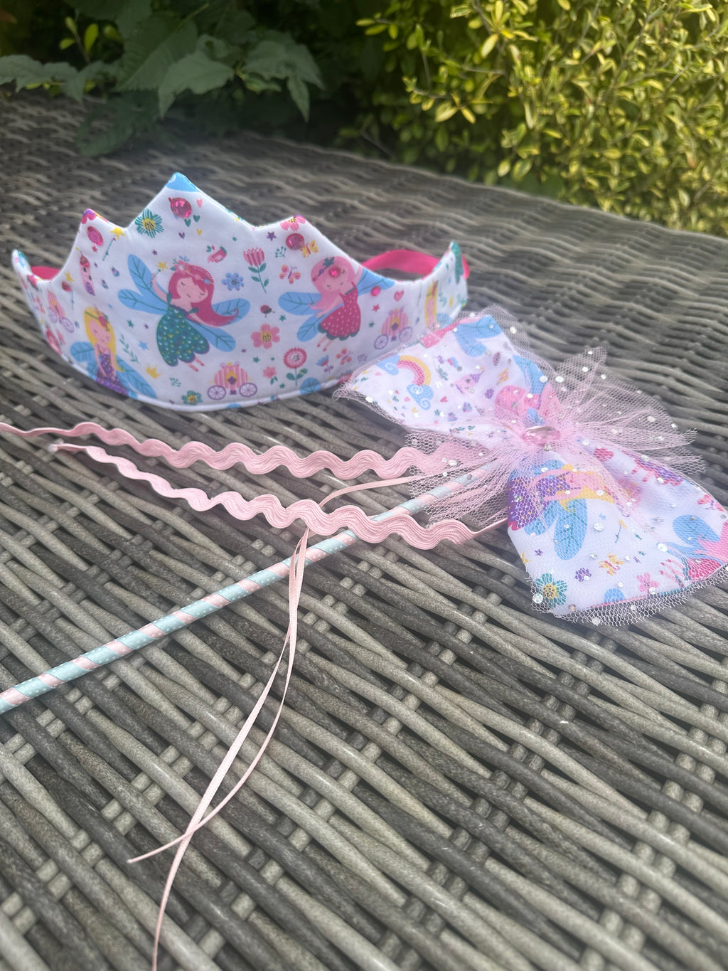 Pastel mermaid fairy crown and matching wand set on a garden table