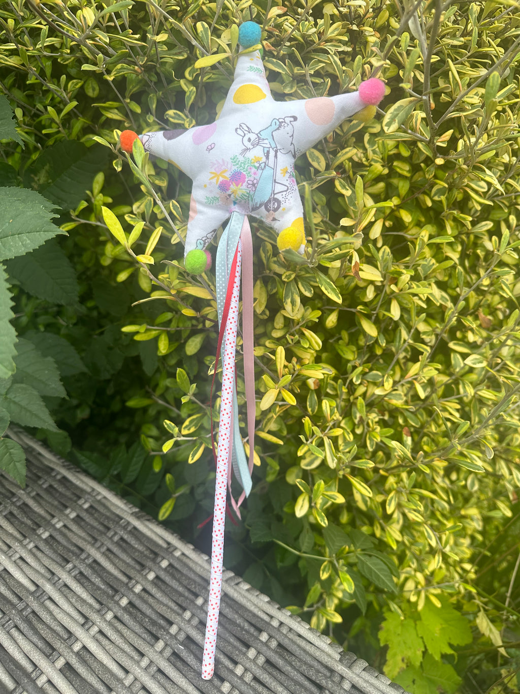 Peter Rabbit fabric star wand with colourful pom-poms and trailing ribbons outdoors