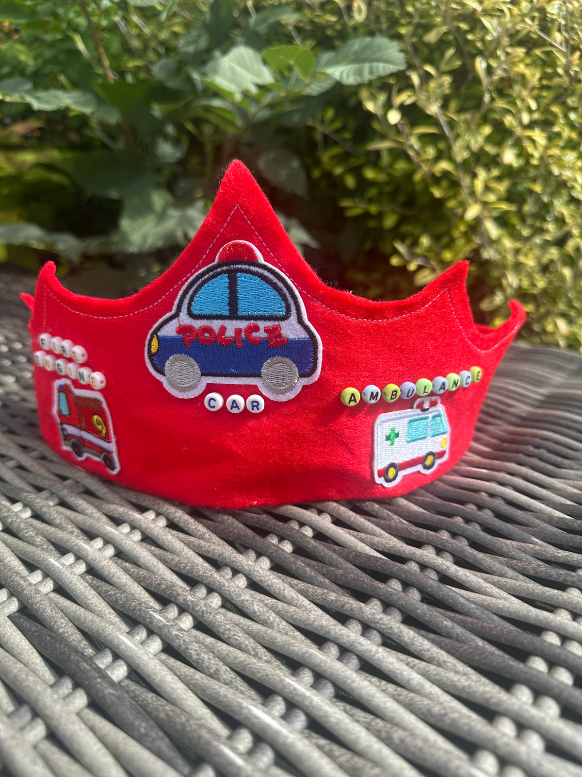 Red felt crown with embroidered police car, fire engine and ambulance patches with bead lettering