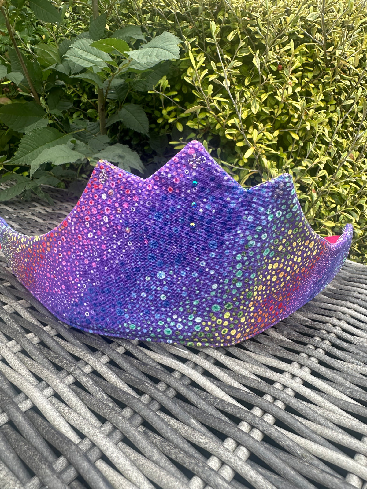 Purple crown with colourful shimmering dot and sequin-style pattern displayed on a garden table