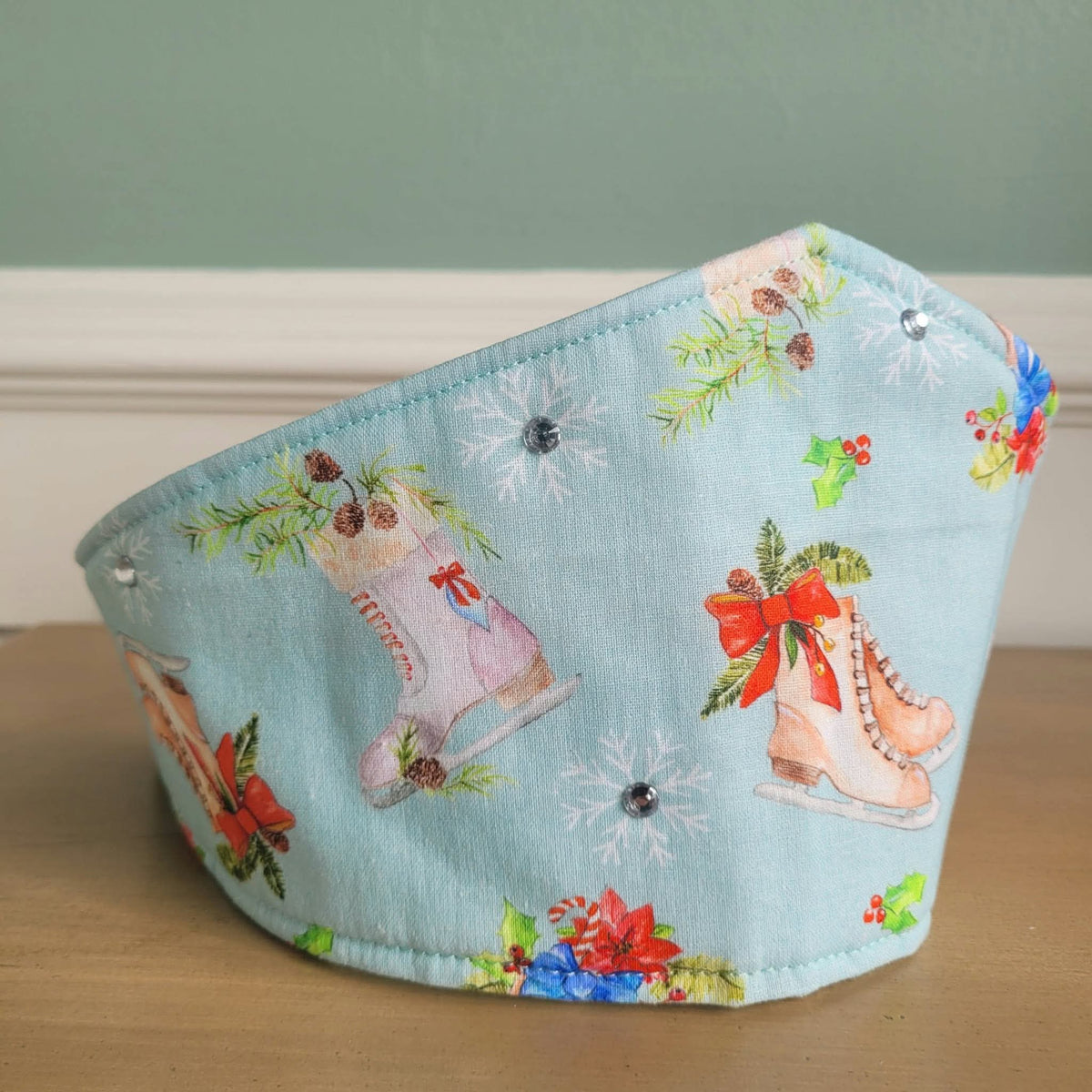 Side view of pale blue ice skate fabric crown with gem accents and holiday motifs