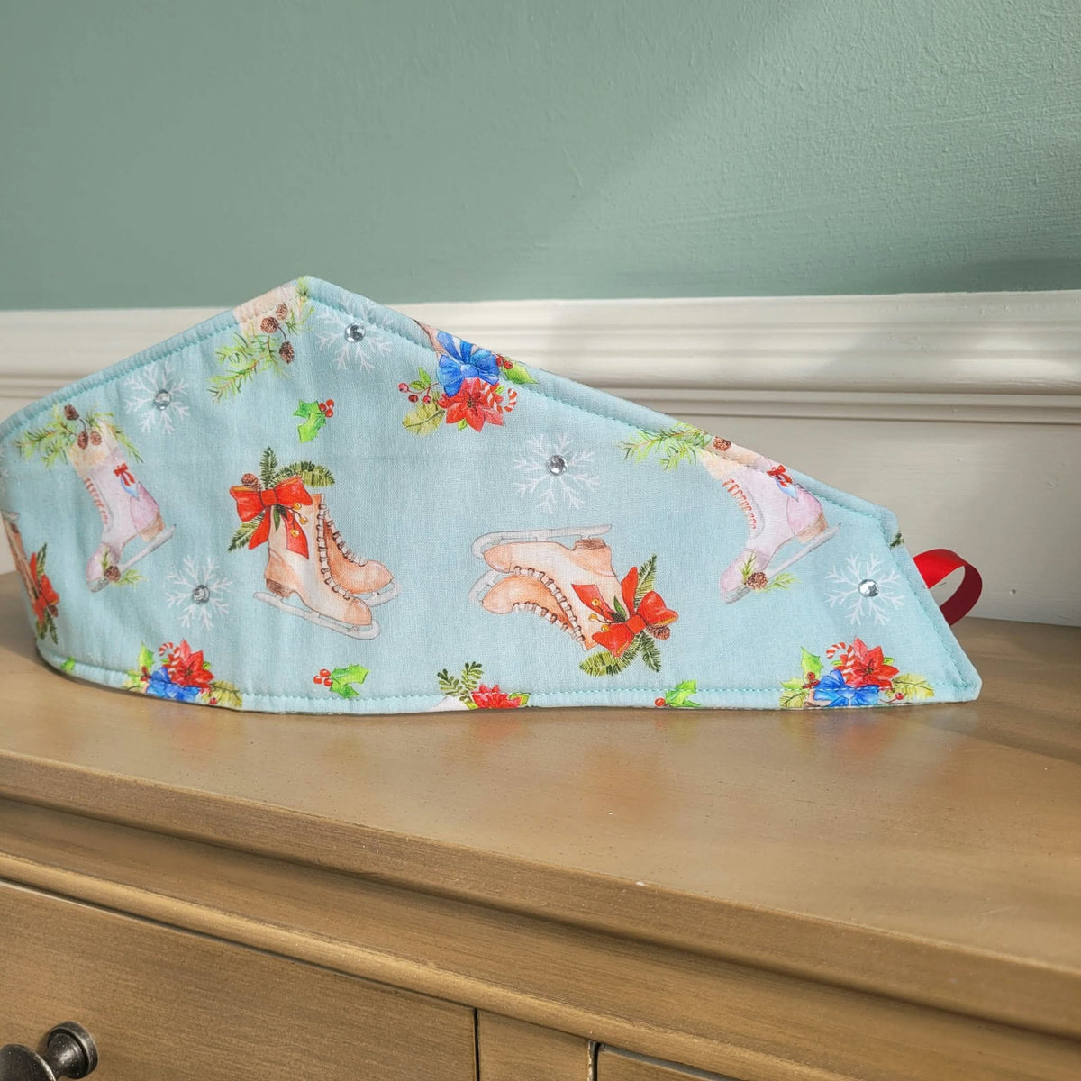 Pale blue pointed fabric crown with festive ice skate print and red ribbon tie